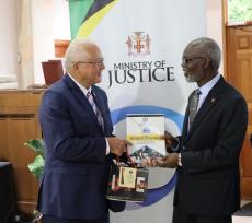Minister of Justice, Hon. Delroy Chuck (left) handing over a copy of the Restorative Justice Policy to Director of Community Service at the Jamaica Union Conference of Seventh Day Adventist Churches, Pastor Adrian Cotterell (right) at the first session of the Restorative Justice Community Impact Consultation, at the Andrews Seventh Day Adventist Church on Thursday April 18.  