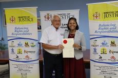 Justice Minister, Delroy Chuck, posing for a photograph with newly commissioned notary public and CEO of the Administrator-General's Department, Stacie-Ann Carty during a brief ceremony at the Ministry on July 25, 2025. 